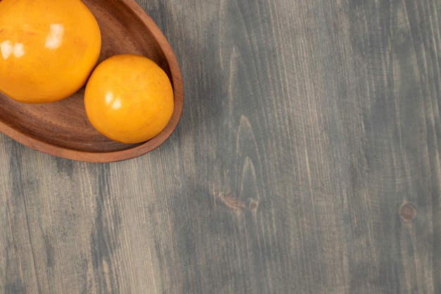 Caquis jugosos deliciosos en una tabla de madera. Foto de alta calidad