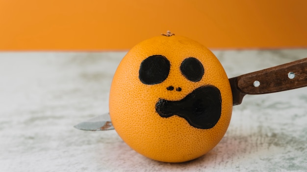 Cara en la foto en la fruta con el cuchillo perforado dentro