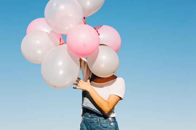 Cara de mujer escondida detrás de globos