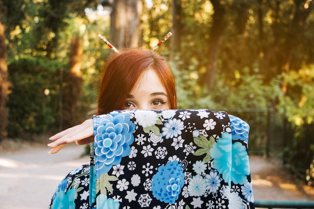 Cara de mujer oculta detrás de la manga del kimono