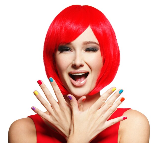 Cara de sorpresa de una mujer joven y bonita con pelos rojos brillantes y uñas multicolores.