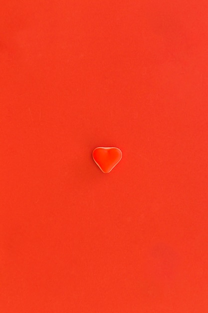 Caramelo en forma de corazón rojo en el centro de fondo rojo