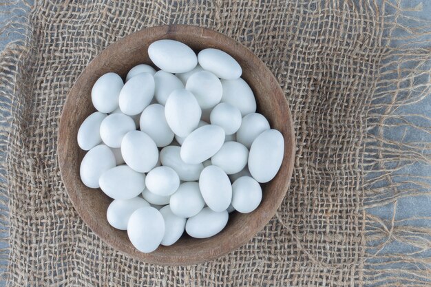 Caramelos blancos en la taza sobre el salvamanteles, sobre la mesa de mármol.