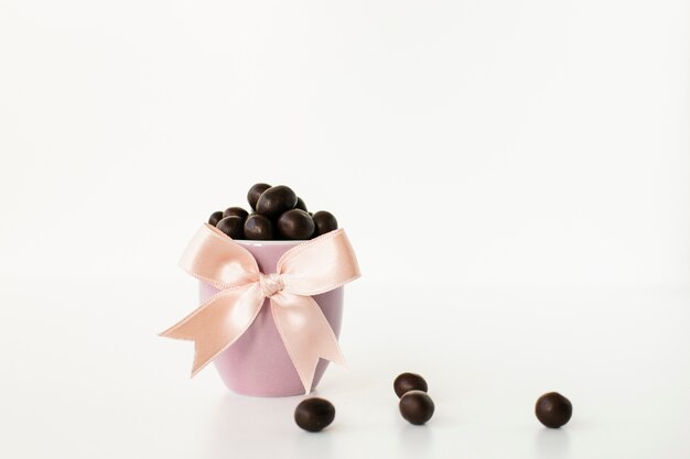 Caramelos de chocolate en un tazón rosa con cinta