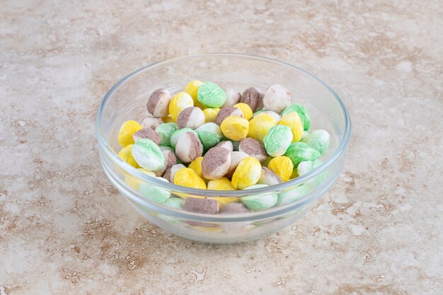 Caramelos de colores en un cuenco, sobre la mesa de mármol.