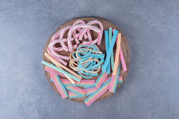 Caramelos de colores en forma de cuerda retorcida sobre un tablero de mesa de mármol.