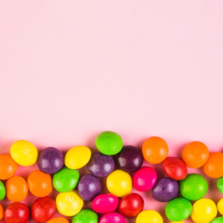 Foto gratuito caramelos dulces coloridos en fondo rosado