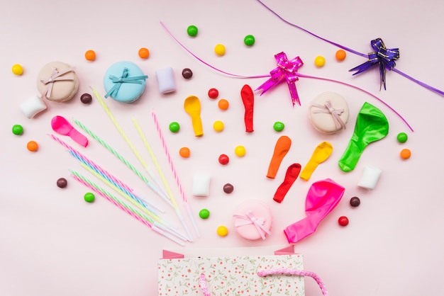 Foto gratuita caramelos dulces; macarrón; globos; y cintas sobre la bolsa de compras