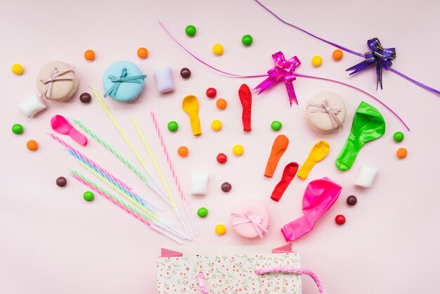 Caramelos dulces; macarrón; globos; y cintas sobre la bolsa de compras