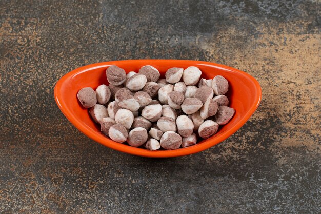 Caramelos dulces marrones en tazón de fuente naranja.