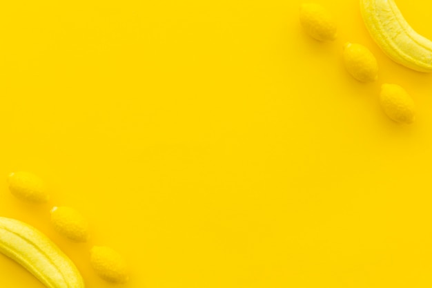 Foto gratuita caramelos dulces de plátano y limón sobre fondo amarillo