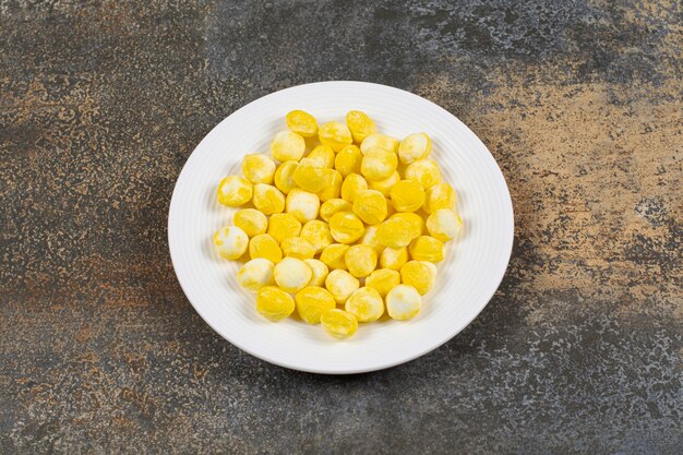 Caramelos duros amarillos en un plato blanco.