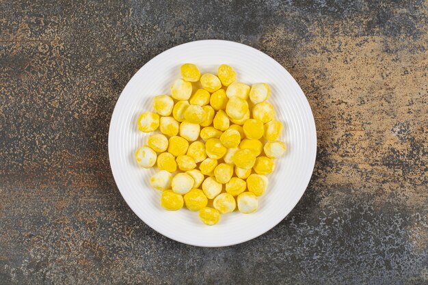 Caramelos duros amarillos en un plato blanco.