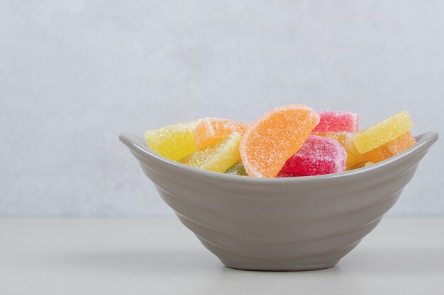Caramelos de gelatina de colores dulces en un tazón sobre superficie beige