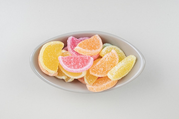 Caramelos de gelatina de colores dulces en un tazón sobre superficie beige