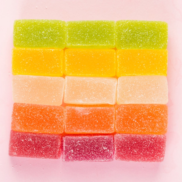 Caramelos de gelatina de colores que forman una forma cuadrada en superficie rosada