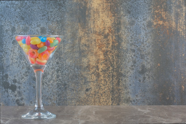 Caramelos de gelatina de colores en vidrio sobre fondo gris.