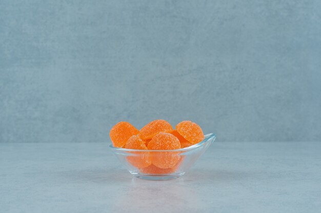 Caramelos de gelatina de naranja dulce con azúcar en una placa de vidrio sobre un fondo blanco. Foto de alta calidad