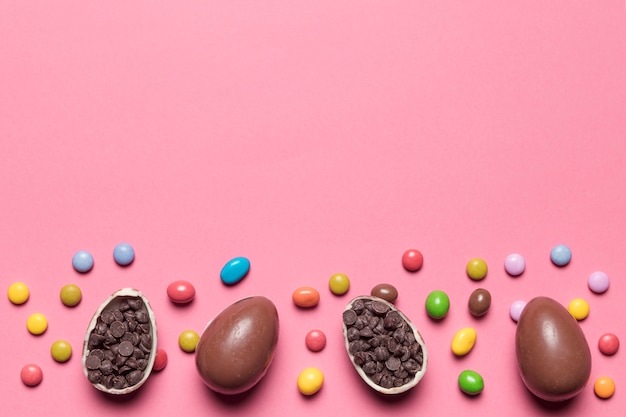 Caramelos de gemas; Huevos de Pascua de chocolate rellenos de chips de choco sobre fondo rosa