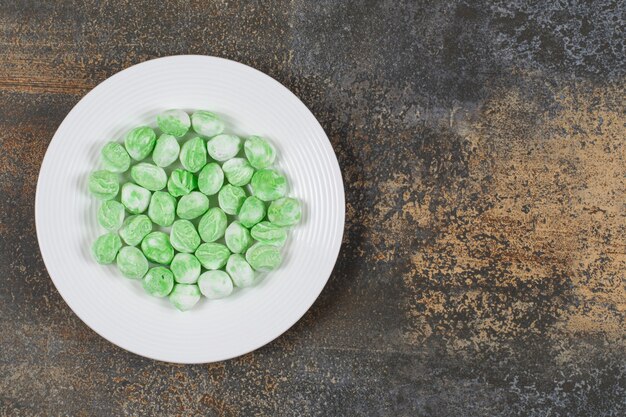 Caramelos de mentol verde en plato blanco.