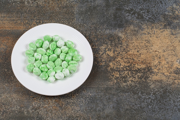 Foto gratuita caramelos de mentol verde en plato blanco.