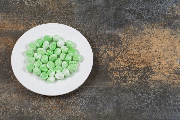 Caramelos de mentol verde en plato blanco.