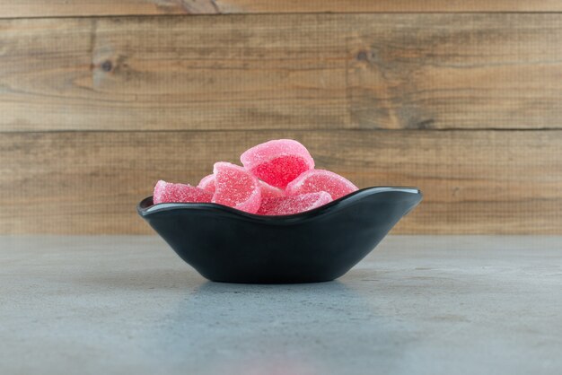 Caramelos de mermelada roja en tazón de fuente negro. Foto de alta calidad