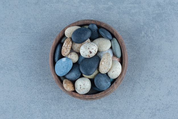 Caramelos de piedra de guijarros en un cuenco, sobre la mesa de mármol.