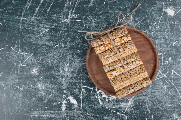 Caramelos quebradizos atados con cuerda sobre placa de madera.