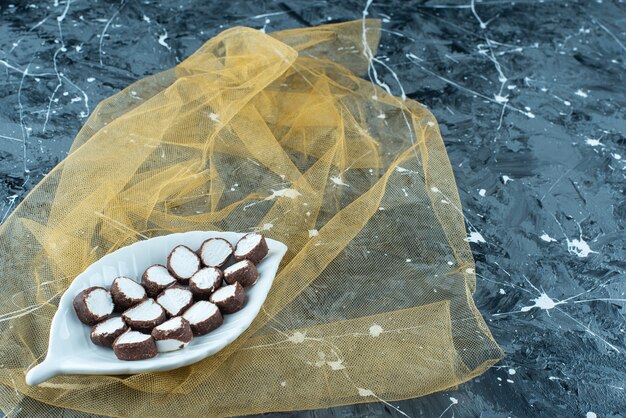 Caramelos en rodajas en un plato sobre un tul, sobre la mesa azul.