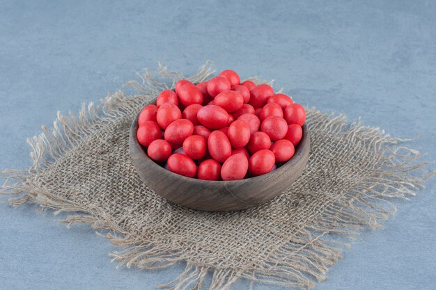 Caramelos rojos en la taza sobre el salvamanteles, sobre la mesa de mármol.