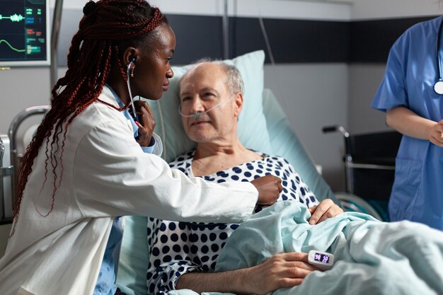 Cardiólogo afroamericano comprobación examinando el corazón del paciente mayor