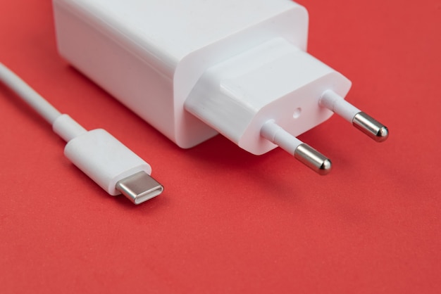 Cargador y cable USB tipo C sobre fondo rojo.