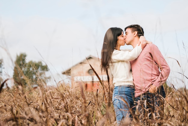 Cariñosa pareja joven de pie besos