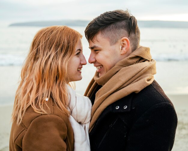 Cariñosa pareja joven sonriente en invierno en la playa