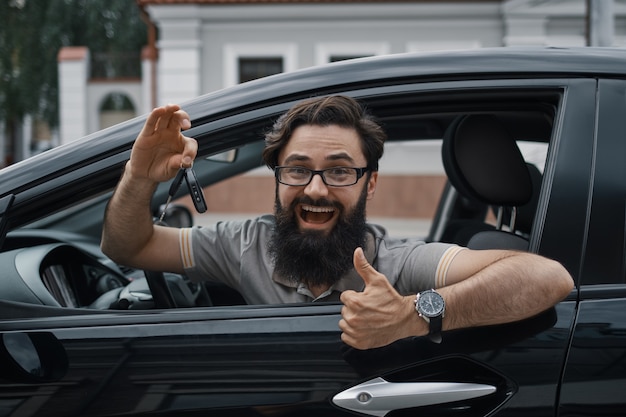 Foto gratuita carismático hombre sosteniendo las llaves del auto mostrando los pulgares para arriba