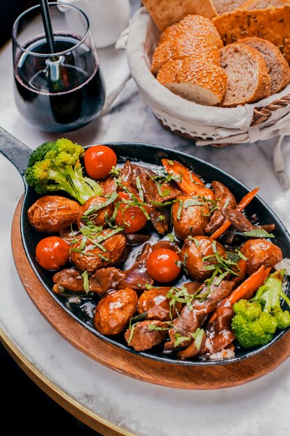 Carne al horno con verduras en un soporte de madera