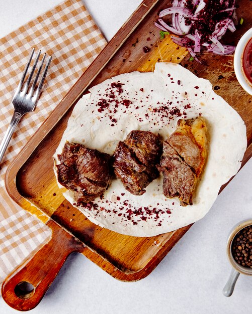 carne asada con cebolla roja en una tabla de madera