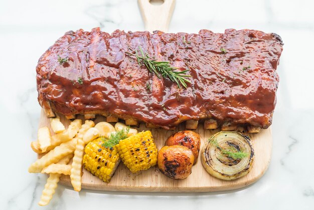 Carne de cerdo a la parrilla con salsa de barbacoa y patatas fritas vegetales y frech en tabla de cortar de madera