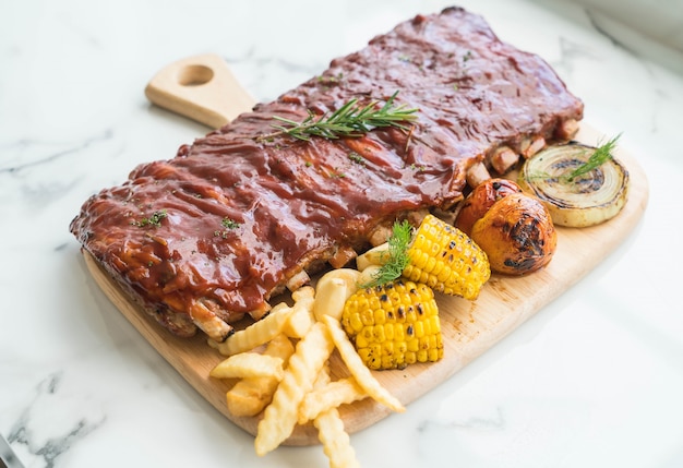 Carne de cerdo a la parrilla con salsa de barbacoa y patatas fritas vegetales y frech en tabla de cortar de madera