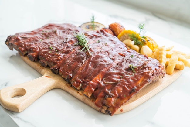 Carne de cerdo a la parrilla con salsa de barbacoa y patatas fritas vegetales y frech en tabla de cortar de madera