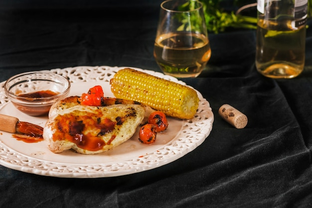 Carne de cerdo servida con tomates cherry y mazorca de maíz en un plato