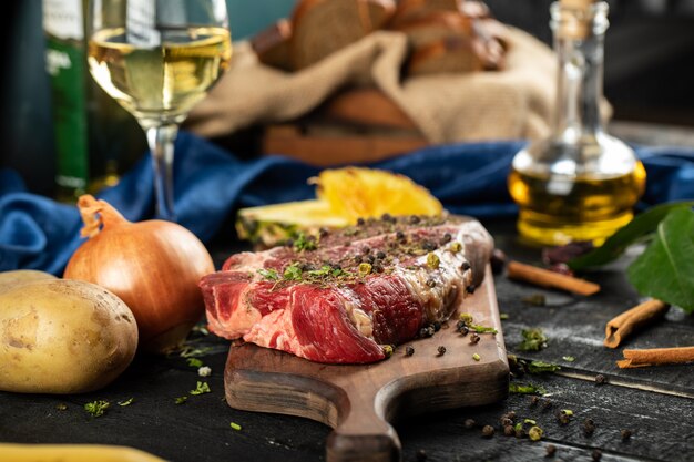 Carne cruda en una tabla de madera con hierbas y especias.