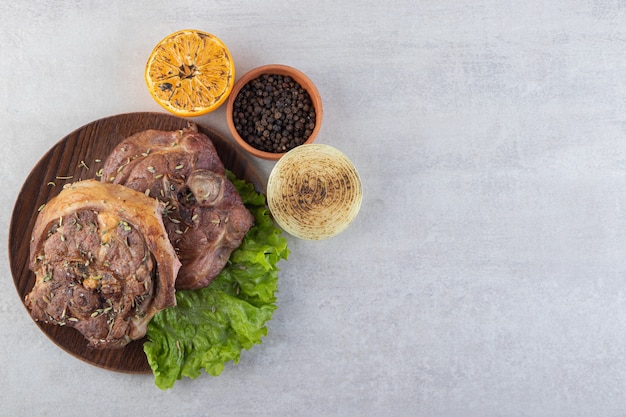 Carne fresca en rodajas con verduras frescas colocadas sobre una mesa de piedra.