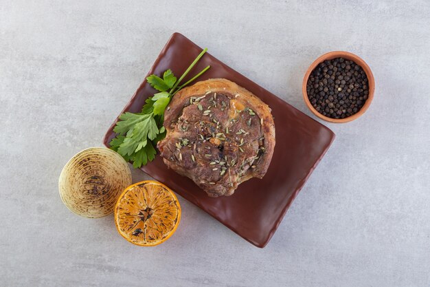 Carne fresca en rodajas con verduras frescas colocadas sobre una mesa de piedra.