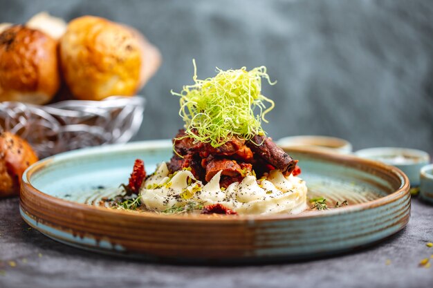 Carne frita colocada sobre puré de papas adornada con pimiento rallado y tomillo