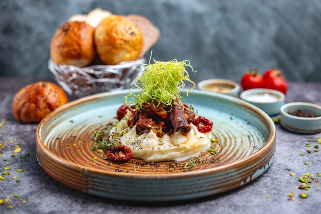 Carne frita colocada sobre puré de papas adornada con pimiento rallado y tomillo