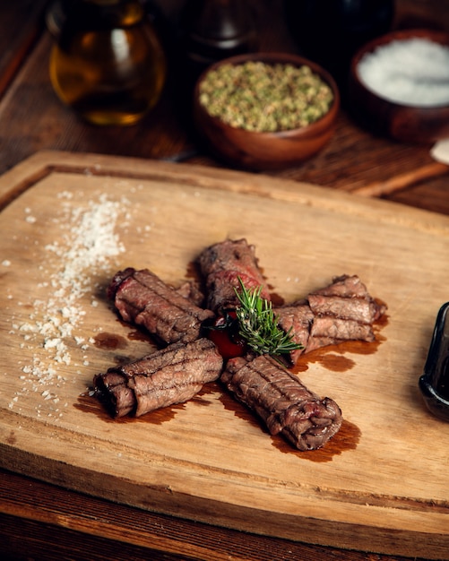 Carne frita enrollada en un rollo sobre una tabla de madera