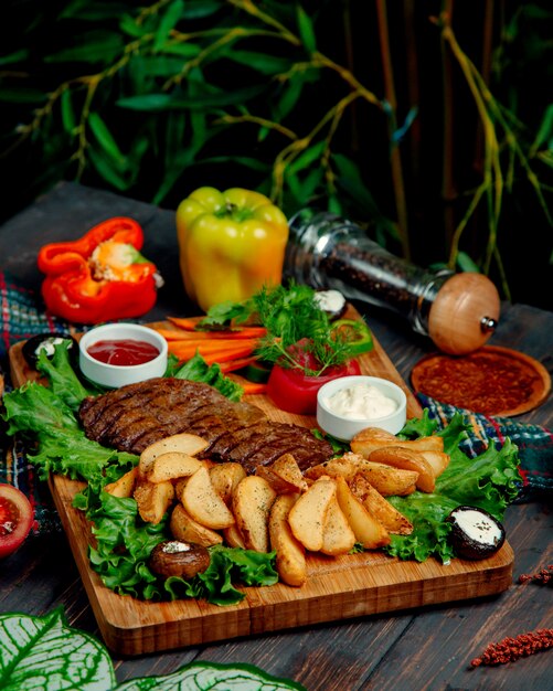 Carne frita y papas en casa sobre una tabla de madera