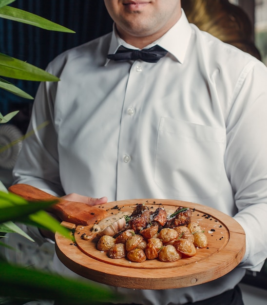 carne frita y patata sobre tabla de madera